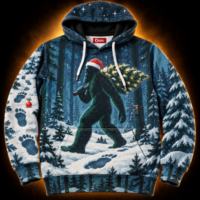 Silent Night hoodie front — Bigfoot in a Santa hat carrying a lit Christmas tree through a snowy moonlit pine forest